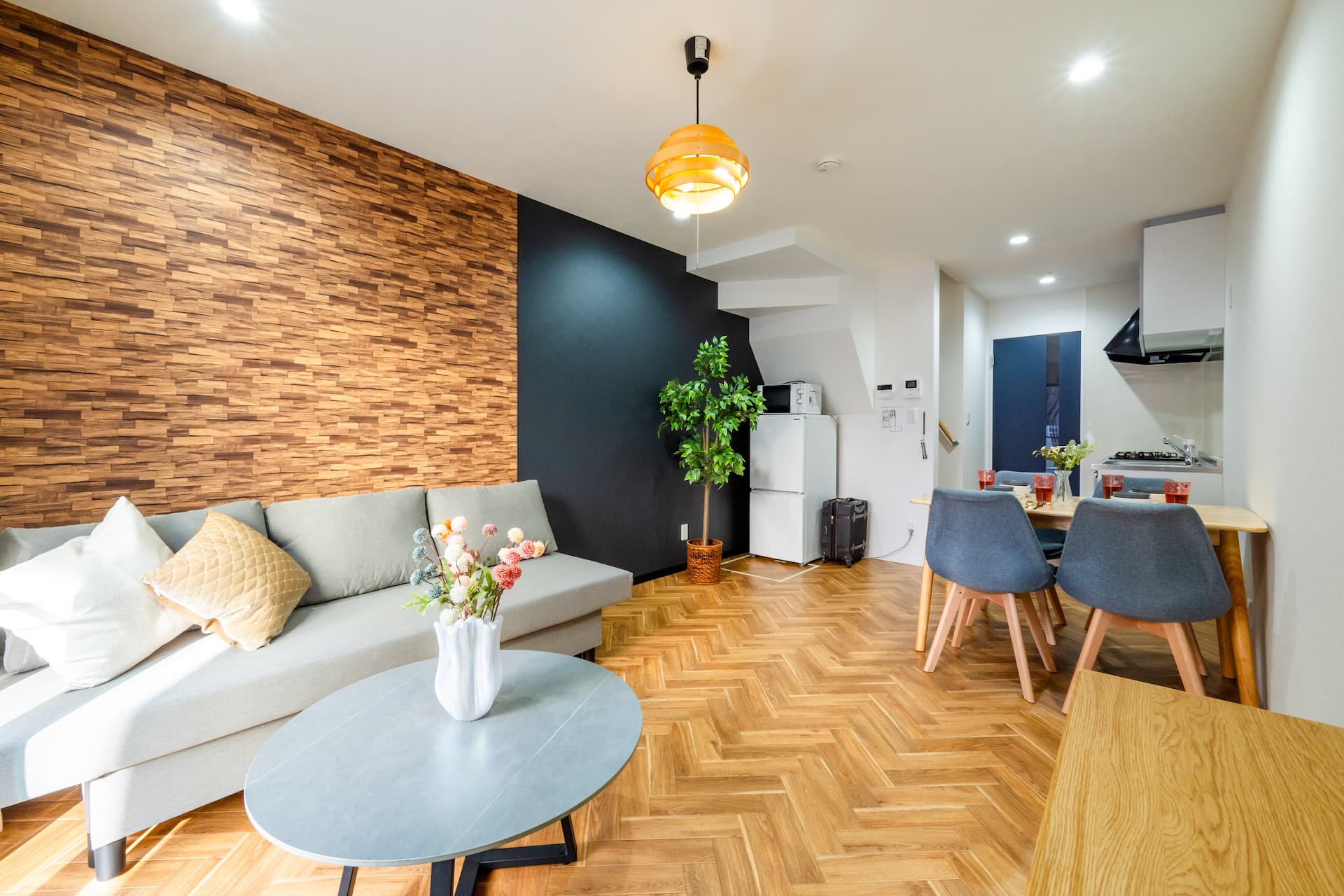 Spacious modern living and dining area at our Namba East Osaka apartment — herringbone floor, designer sofa, full kitchen